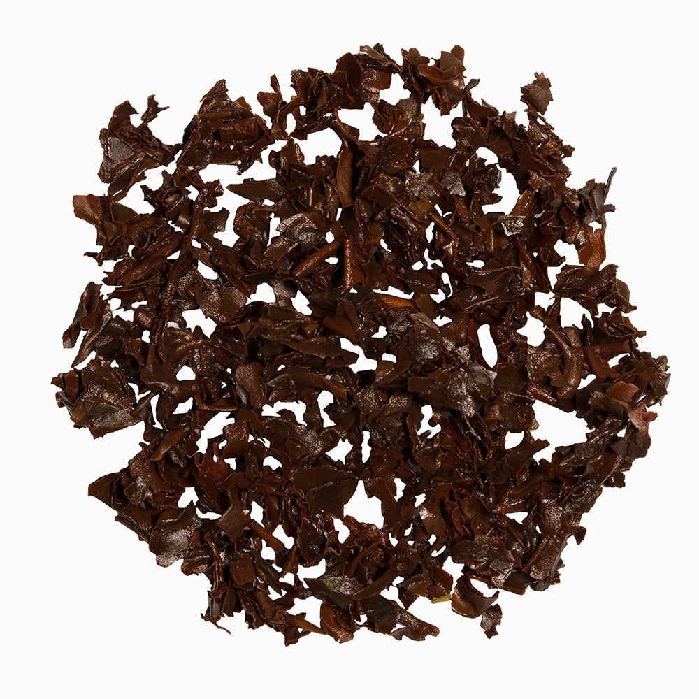 Brown tea leaves on white surface — showcasing Kulukkumalai’s earthy character.